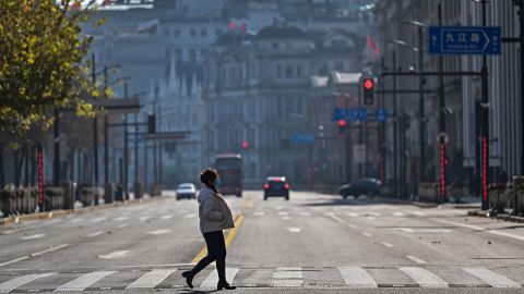 A woman crosses a street on the Bund in the Huangpu district in Shanghai on December 21, 2022. 
