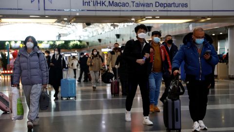 Gezginler, 27 Aralık 2022'de Pekin, Çin'deki Pekin Başkent Uluslararası Havalimanı'nda valizleriyle yürüyor.