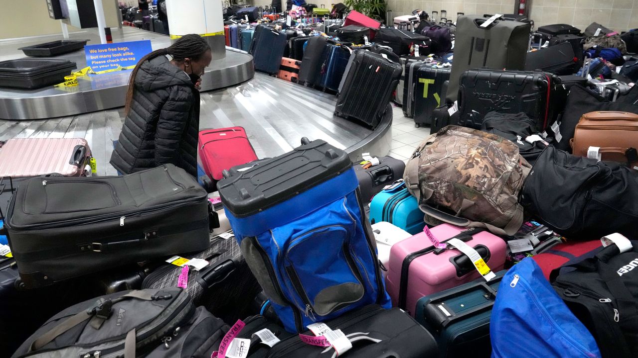 A person walks through luggage piled up around an unmoving baggage carousel inside the Southwest Airlines terminal at St. Louis Lambert International Airport on Wednesday..