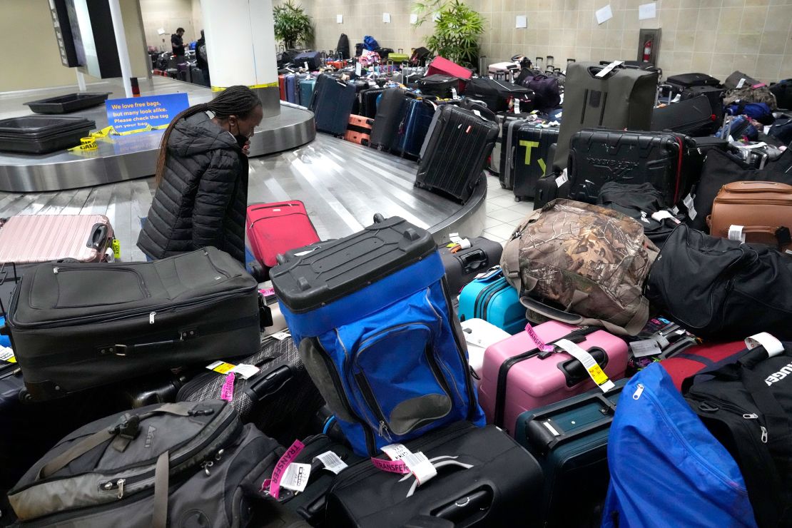 A person walks through luggage piled up around an unmoving baggage carousel inside the Southwest Airlines terminal at St. Louis Lambert International Airport on Wednesday..