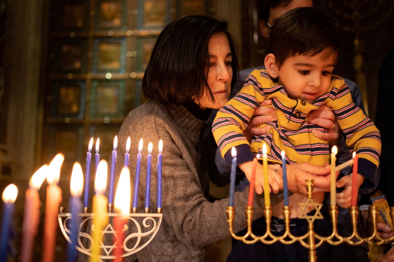Andrea Selbst lights a Hanukkah candle with her 3-year-old grandson Miles before participating in a Shabbat service in Philadelphia on Friday, December 23.