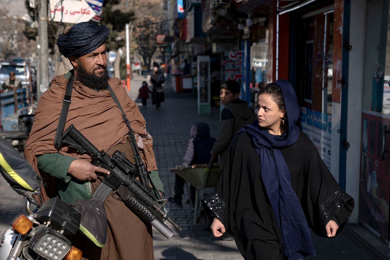 A woman walks past a Taliban fighter in Kabul, Afghanistan, on Monday, December 26. Although the Taliban repeatedly claimed it would protect the rights of girls and women following its takeover of the country in August 2021, <a href="https://www.cnn.com/2022/12/27/asia/taliban-un-security-council-women-freedom-intl-hnk/index.html" target="_blank">the group has done the opposite</a>, stripping away the hard-won freedoms for which women have fought tirelessly over the past two decades.