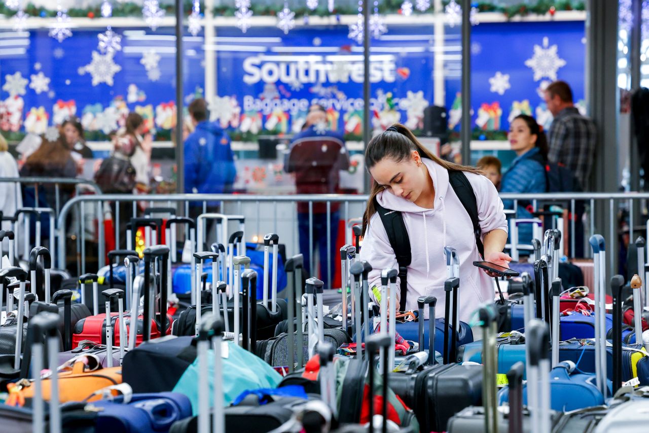 Pristine Floyde searches for a friend's suitcase in a baggage holding area at Denver International Airport on Wednesday, December 28. More than 90% of Wednesday's US flight cancellations were Southwest Airlines flights, according to flight tracking website FlightAware.