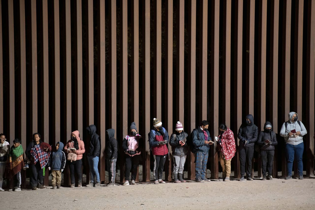 Migrants seeking asylum line up at a gap in the US-Mexico border fence near Somerton, Arizona, to be processed on Monday, December 26.