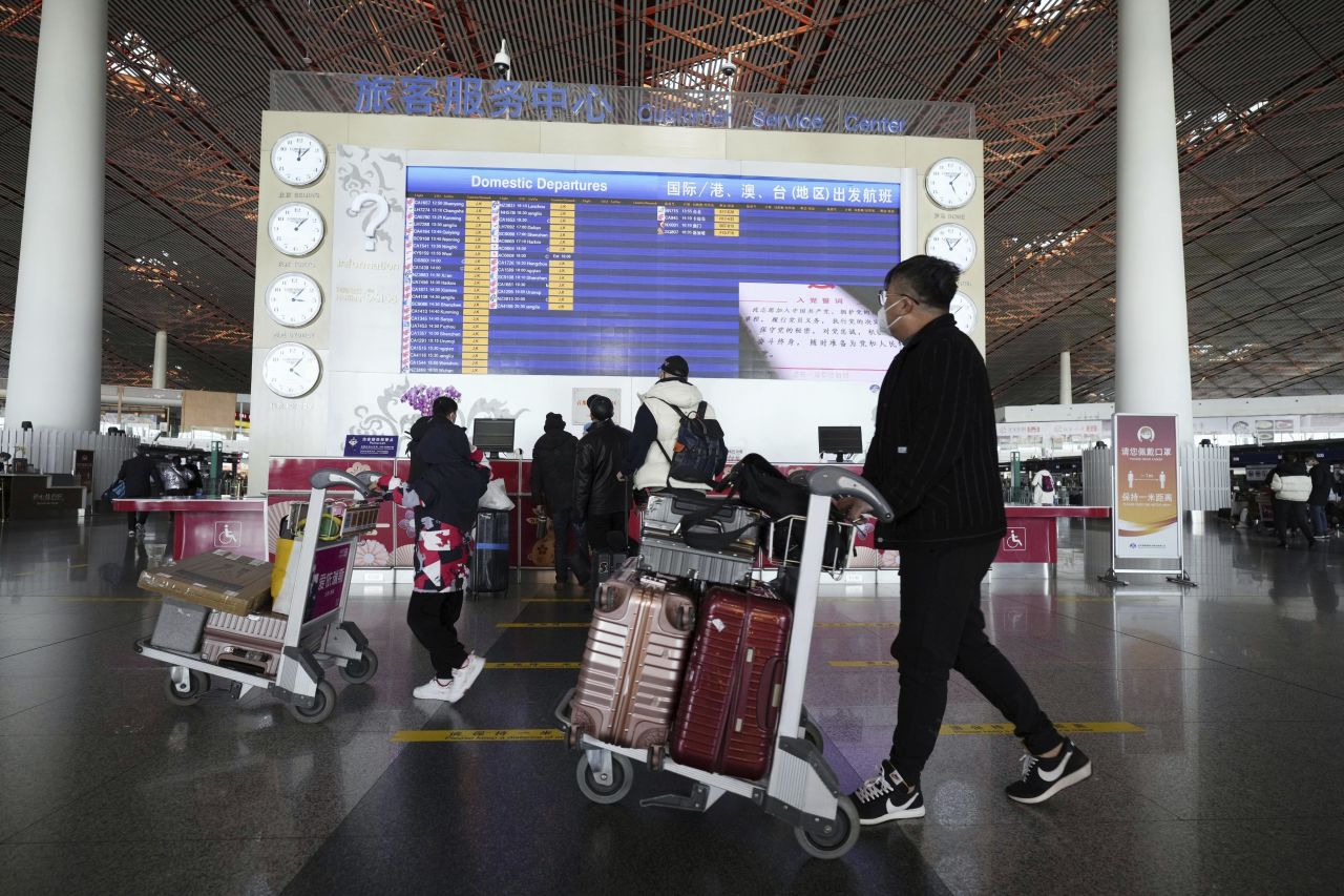 People walk with suitcases through a departure lobby the Beijing airport on December 27.