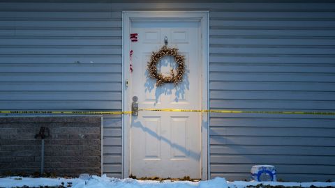 The front door has a red evidence marker and yellow police tape wrapped around it.