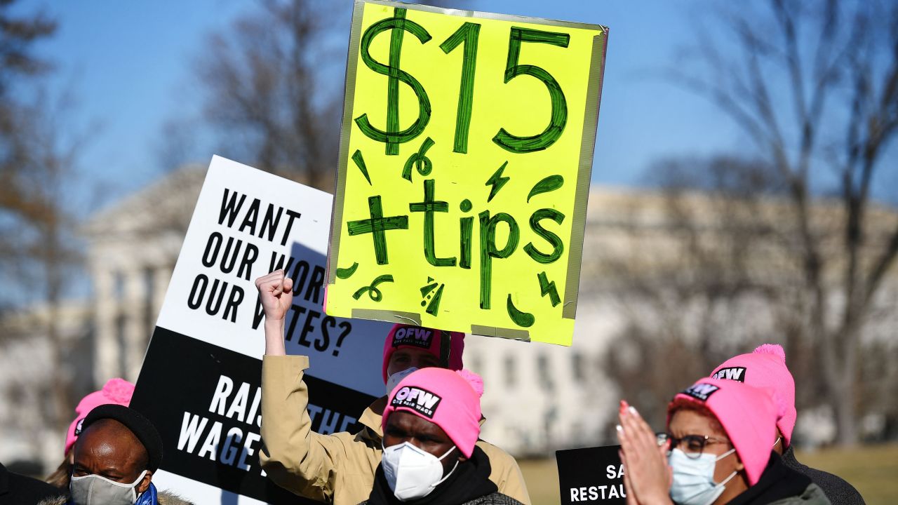 An activist holds a placard demanding a $15/hour minimum wage and tips for restaurant workers during a rally to call for additional relief for restaurants to allow them to pay workers a full minimum wage with tips, at the House Triangle of the US Capitol in Washington, DC on February 8, 2022.