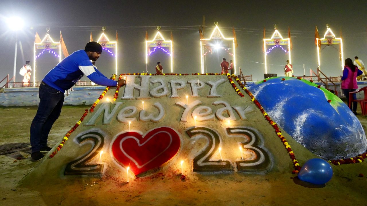 A man lights candles on a sand sculpture in Prayagraj, India.