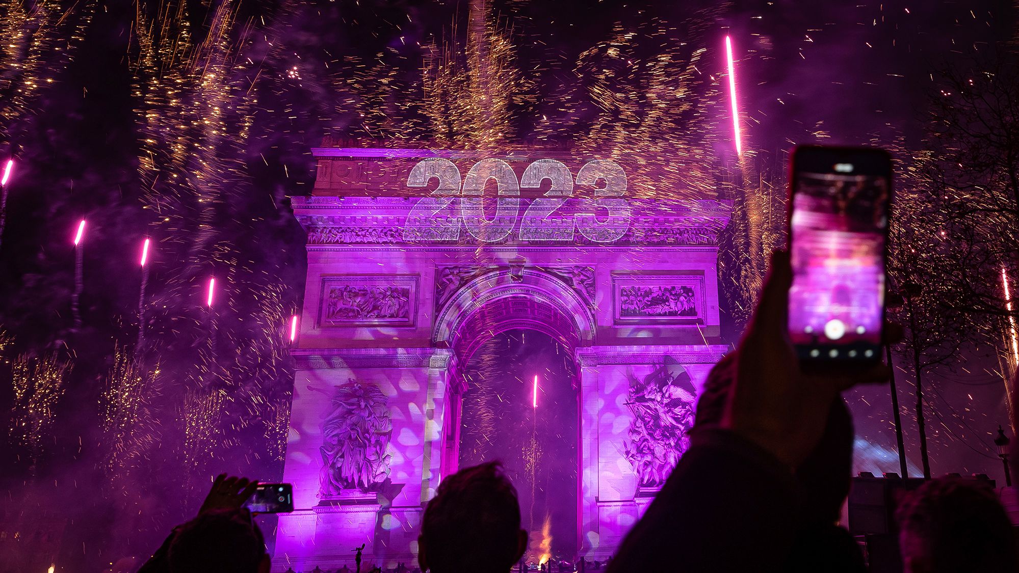Revelers photograph fireworks over the Arc de Triomphe as they celebrate the new year in Paris.