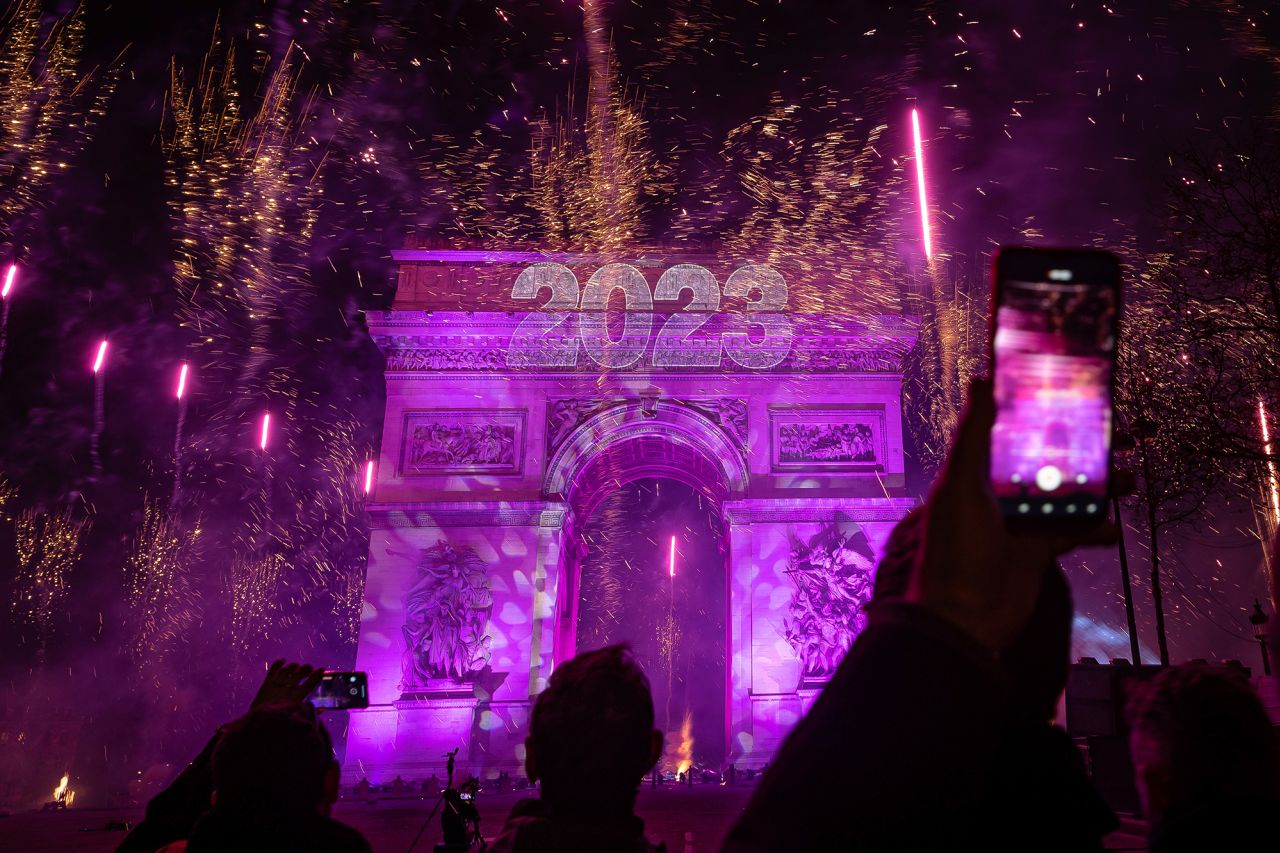 Revelers photograph fireworks over the Arc de Triomphe as they celebrate the new year in Paris.