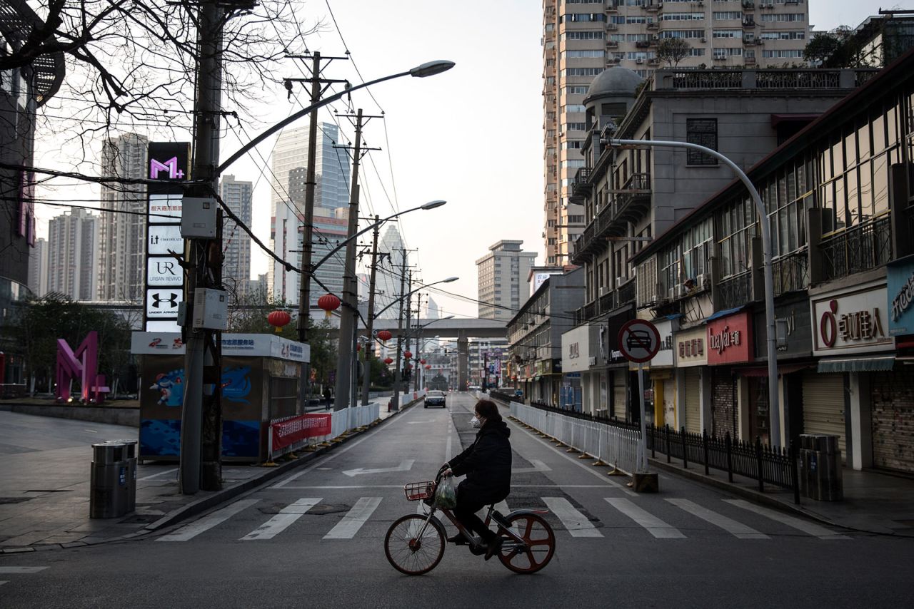 A women wears a protective mask as she ride a bicycle in the empty business street on February 13 in Wuhan, China.