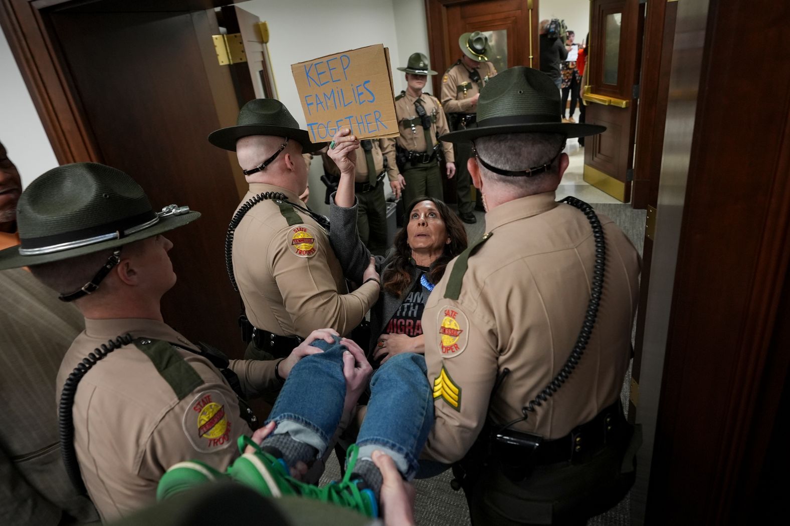 Ashley Warbington, holding a sign that says “keep families together,” is carried out of a House committee meeting by state troopers in Nashville, Tennessee, on Wednesday, January 29. At least three woman were ejected from the meeting on immigration, <a href="index.php?page=&url=https%3A%2F%2Fapnews.com%2Farticle%2Fimmigration-bill-tennessee-republican-17af910d31b325516da02f0ff9a5c853" target="_blank">according to the Associated Press</a>.