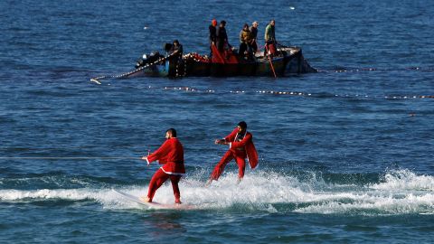 Palestinians dressed in Santa Claus outfits surf in the sea off the coast of Gaza City on December 29, 2022.