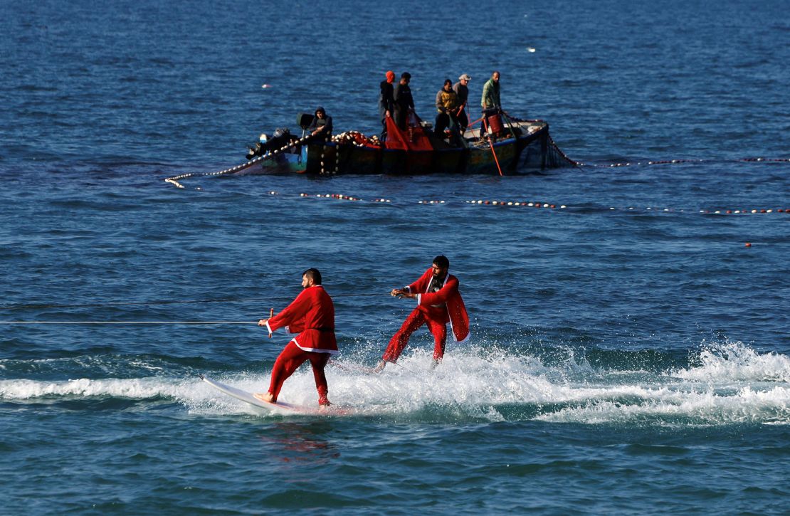Palestinians dressed in Santa Claus outfits surf in the sea off the coast of Gaza City on December 29, 2022.