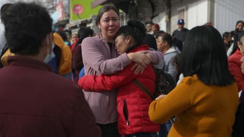 Relatives of inmates gather outside the prison, hugging and consoling each other amid news of the incident within.