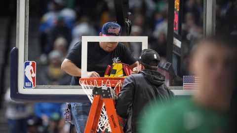 Workers struggle to replace the rim after it was bent during a dunk by Boston Celtics' Robert Williams III.