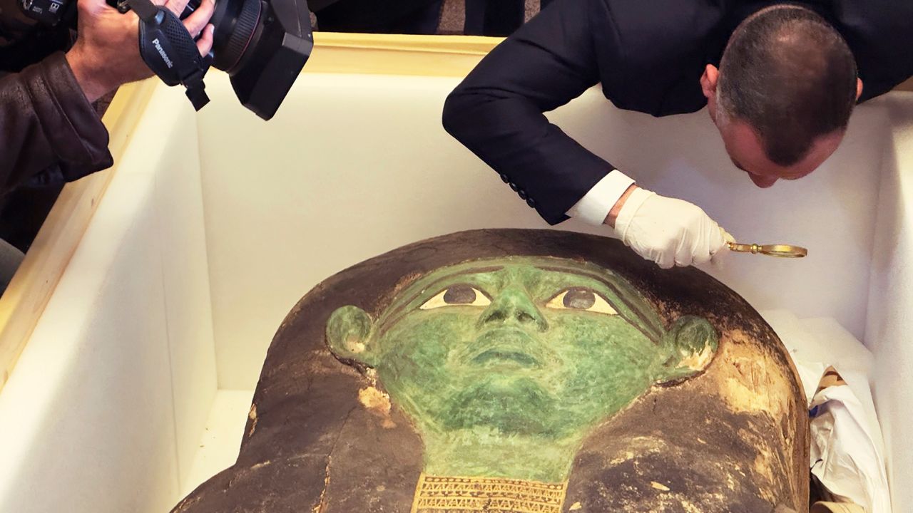 Mostafa Waziri of the Supreme Council of Antiquities takes a look with a magnifier at the ancient wooden sarcophagus during a handover ceremony at the foreign ministry in Cairo on Monday. 