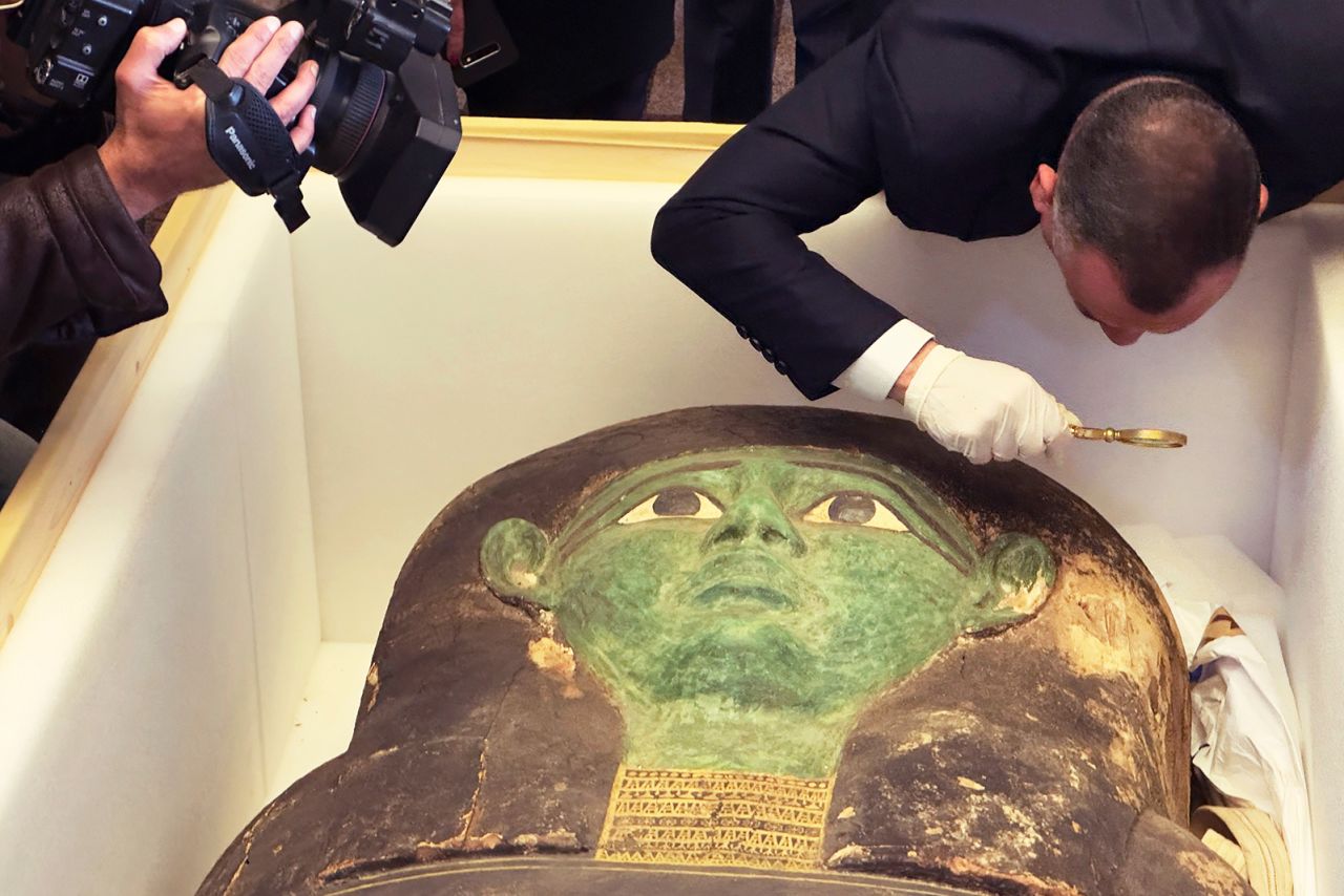 Mostafa Waziri of the Supreme Council of Antiquities takes a look with a magnifier at the ancient wooden sarcophagus during a handover ceremony at the foreign ministry in Cairo on Monday.