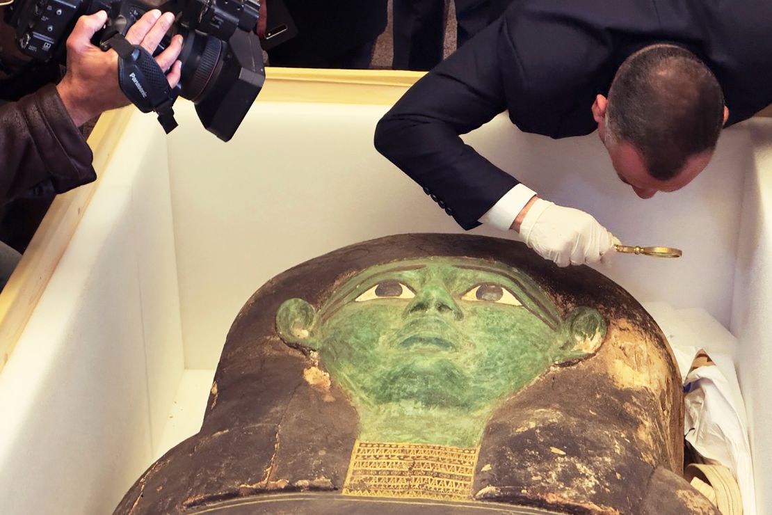 Mostafa Waziri of the Supreme Council of Antiquities takes a look with a magnifier at the ancient wooden sarcophagus during a handover ceremony at the foreign ministry in Cairo on Monday. 