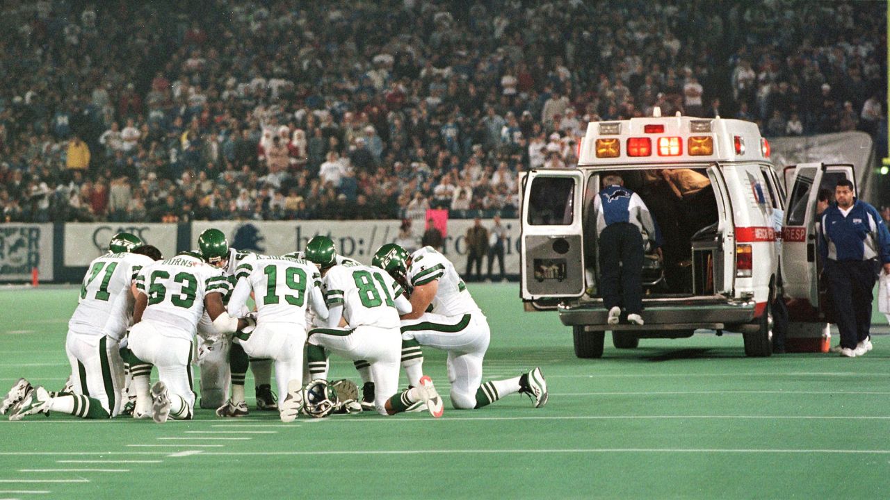Members of the New York Jets kneel in a circle and pray as Detroit Lions linebacker Reggie Brown is taken away in an ambulance on December 21, 1997.