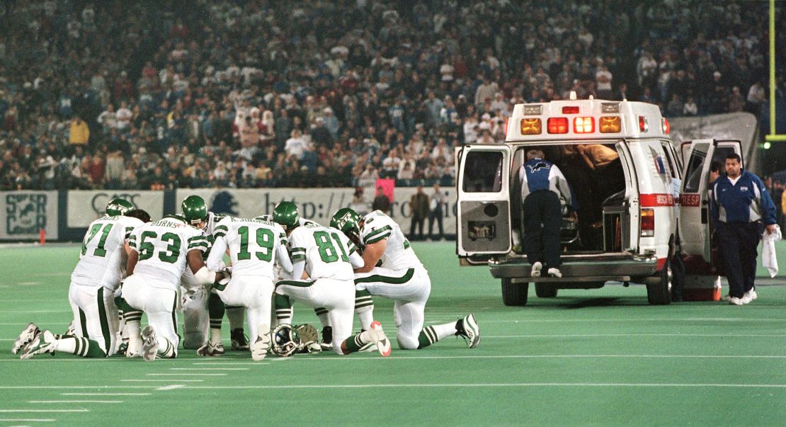 Members of the New York Jets kneel in a circle and pray as Detroit Lions linebacker Reggie Brown is taken away in an ambulance on December 21, 1997.