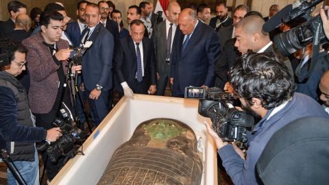 Egyptian Foreign Minister Sameh Shoukry and head of Egypt's Supreme Council of Antiquities Mostafa Waziri are surrounded by journalists as they inspect a wooden sarcophagus, which was handed over by the US in a ceremony on Monday in Cairo, Egypt.  