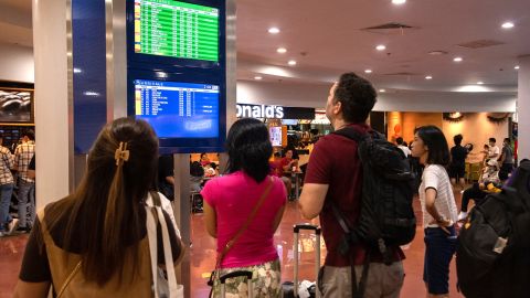 Passengers look at a screen showing flight information at terminal 3 of Ninoy Aquino International Airport in Pasay, Metro Manila on January 1, 2023. 