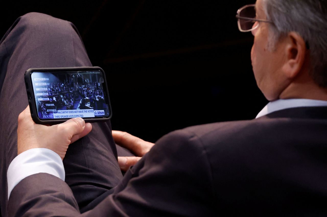 A Republican on the House floor also watches the second round of voting on his phone.