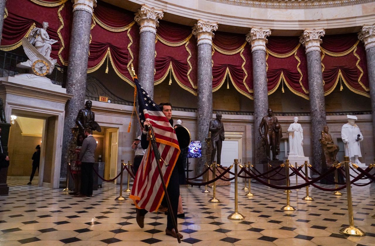 A congressional staff member carries an American flag though the Capitol's Statuary Hall on Tuesday.