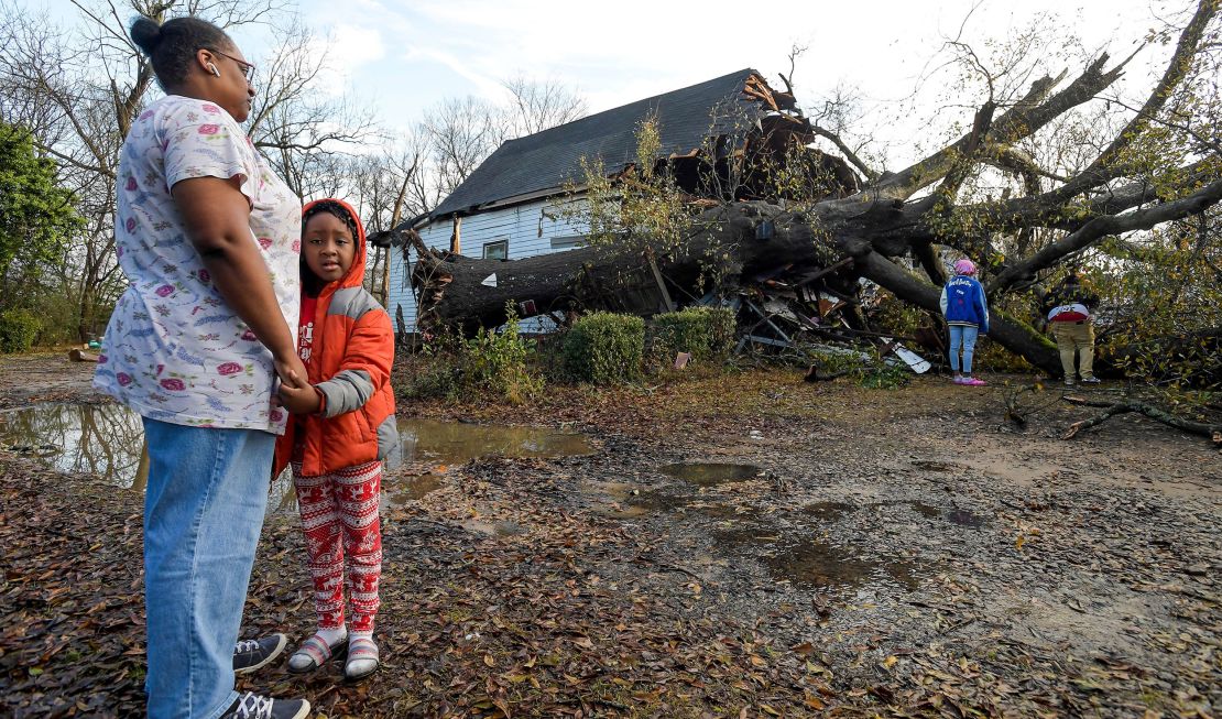 Tara Williams stands with her grandson Major Williams on Wednesday after a large tree fell on a home in Montgomery, Alabama, during a powerful overnight storm.