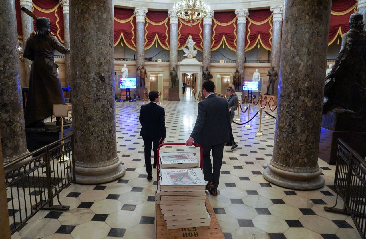 House staff wheel a large cart of pizzas through Statuary Hall late on Tuesday night. McCarthy continued to negotiate Tuesday night, sources said, in an effort to get to 218 votes.