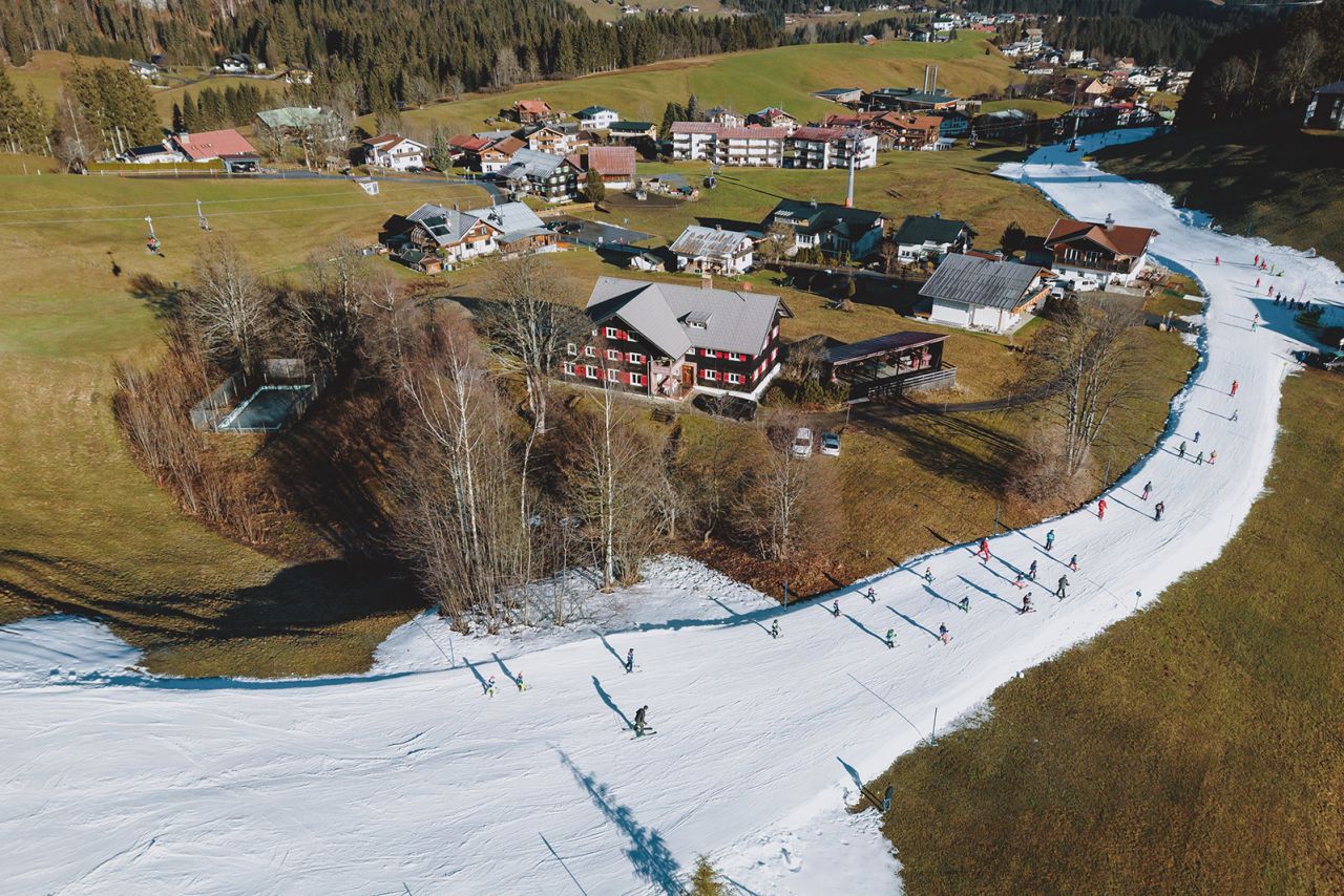 People ski down a slope in Riezlern, Austria, on Friday, December 30. There was a lack of snow in the area following some warm weather.
