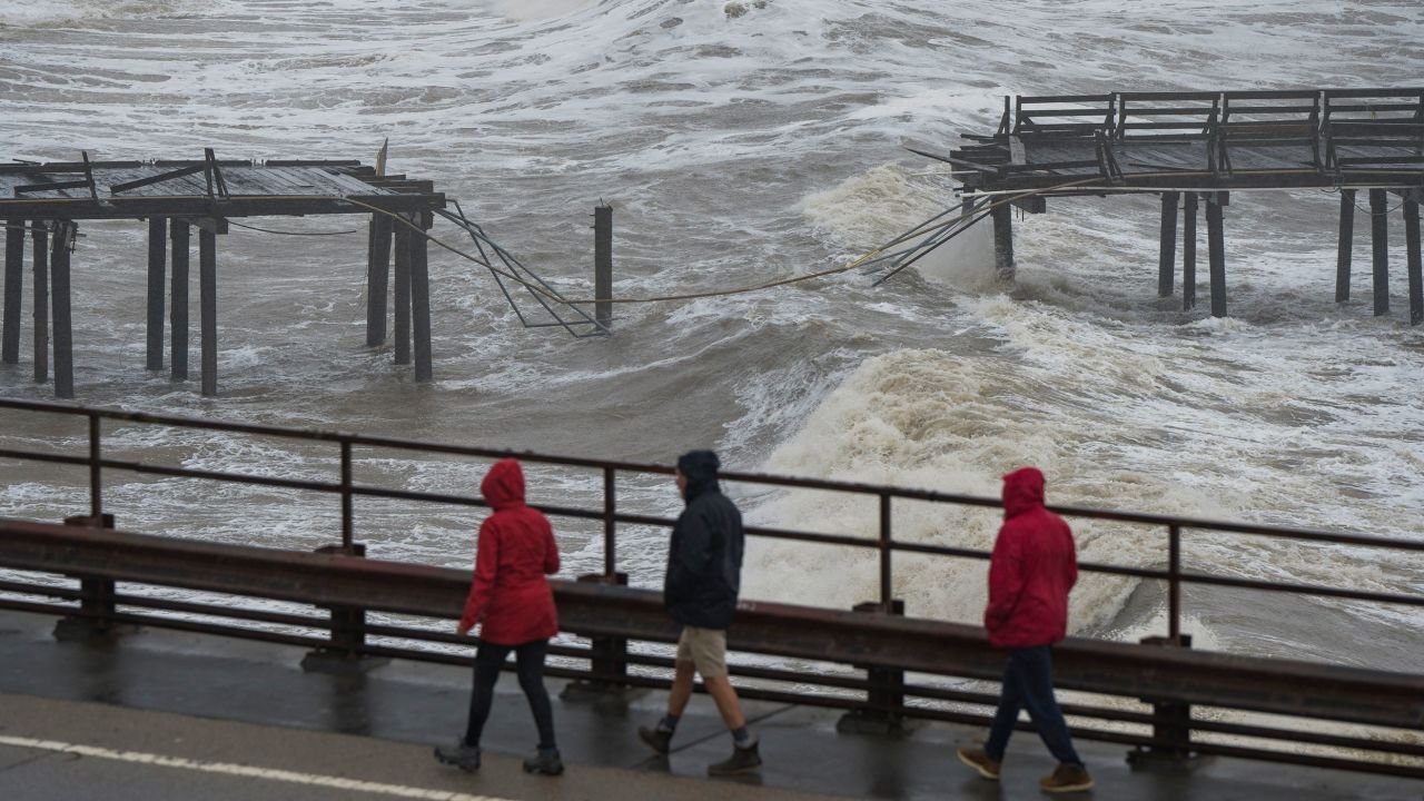 People walk along Cliff Drive to view the Capitola Wharf damaged by heavy storm waves in Capitola on January 5, 2023. 