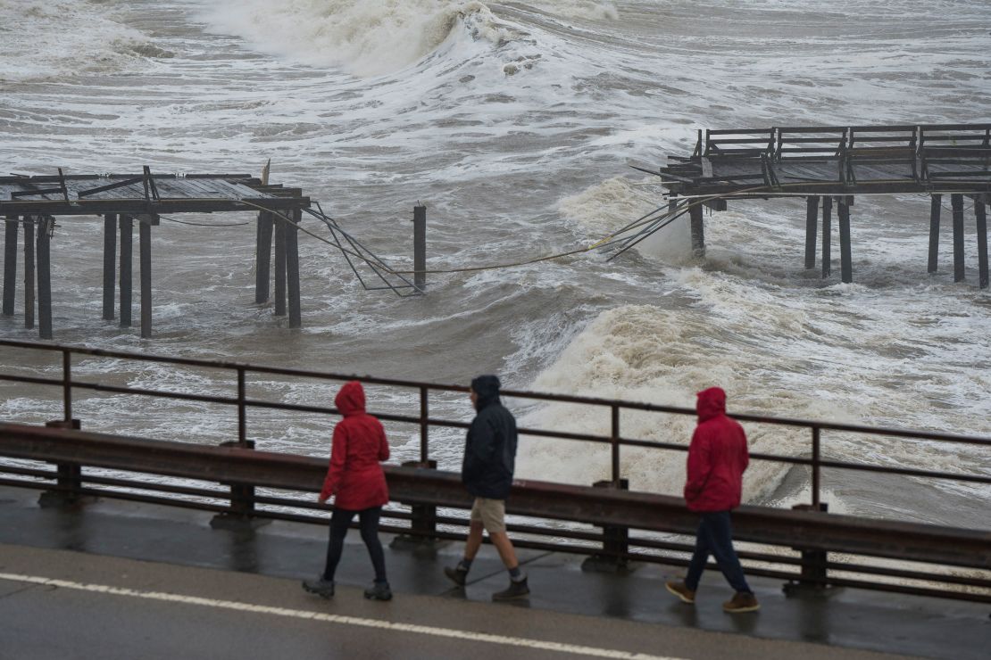 People walk along Cliff Drive to view the Capitola Wharf damaged by heavy storm waves in Capitola on January 5, 2023. 