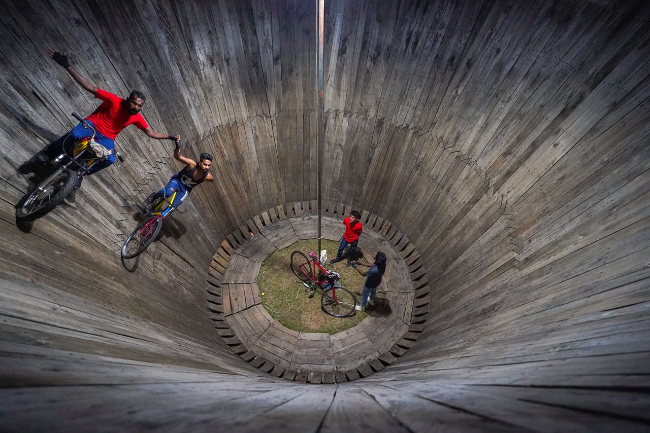 Two men perform on a "Wall of Death" in Colombo, Sri Lanka, on Friday, December 30. The performers put on a show by riding motorcycles and bicycles in the makeshift wooden ring.