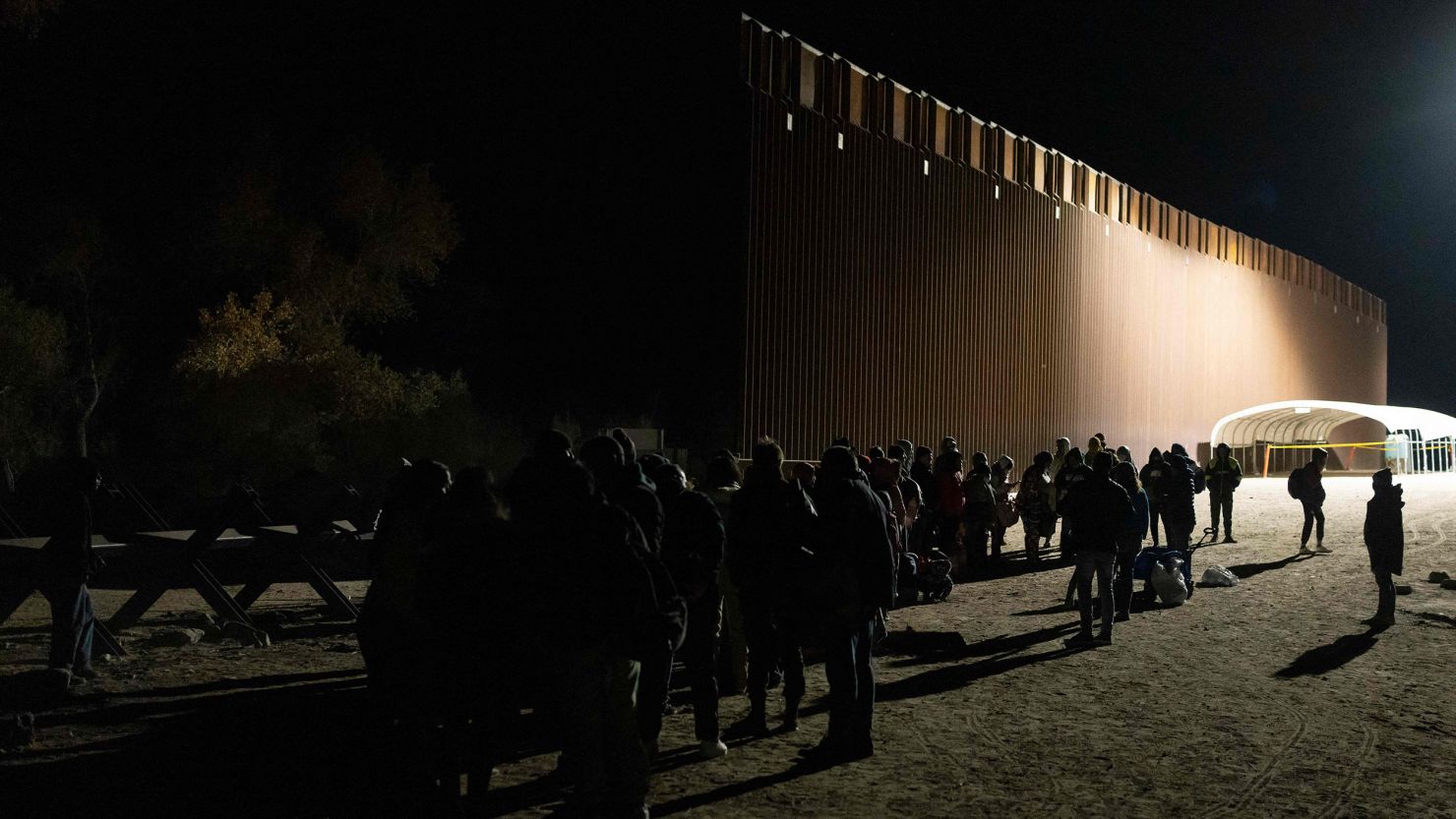 Asylum-seekers line up to be processed by US Customs and Border Patrol agents at a gap in the US-Mexico border fence near Somerton, Arizona, on December 26, 2022. 