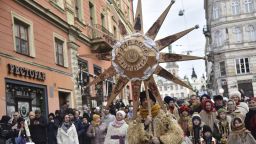 Ukrainians sing Christmas carols as they carry decorated stars of Bethlehem and sheaves of wheat in their hands during a festive parade in Lviv on January 6, 2022.