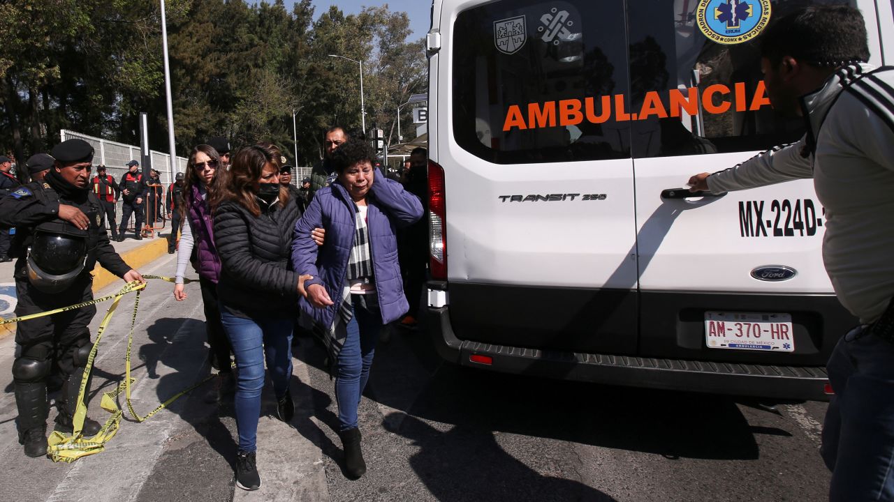 A woman is helped to reach an ambulance after two subway trains collided at a subway station in Mexico City on January 7, 2023.