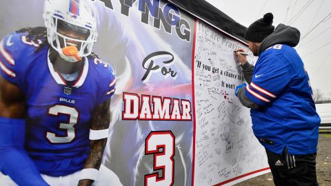 ファンは、日曜日にハイマーク スタジアムの外で、バッファロー ビルズの安全性であるダマー ハムリンをサポートするメッセージが書かれたポスターに署名します。