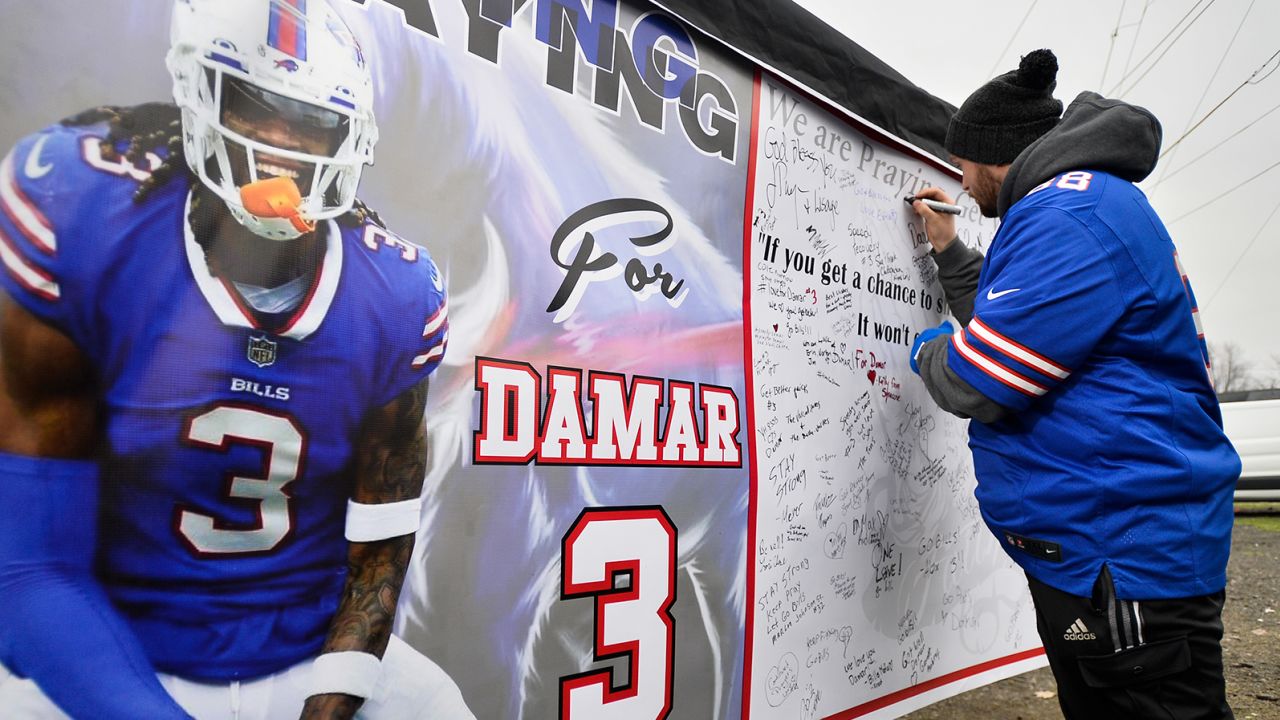 Fans sign a poster with messages of support for Buffalo Bills safety Damar Hamlin outside Highmark Stadium Sunday.