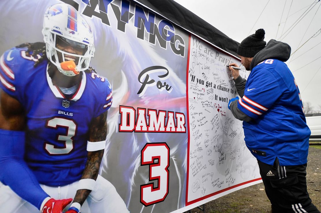 Fans sign a poster with messages of support for Buffalo Bills safety Damar Hamlin outside Highmark Stadium Sunday.