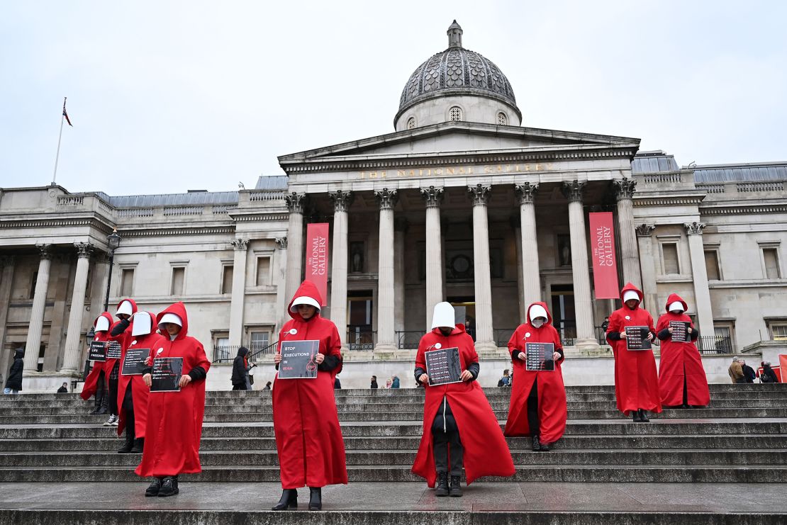 Protesters wearing 'Handmaid's Tale' costumes hold placards during a silent march in central London on January 7 to raise awareness about the recent women-led uprising in Iran.