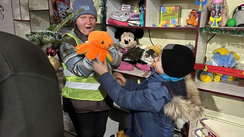 City volunteer Tetiana Scherbak, hands a toy to the only child in the shelter.