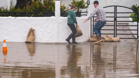 Owners of a restaurant in Aptos, California, place sandbags in front of their establishment Monday.