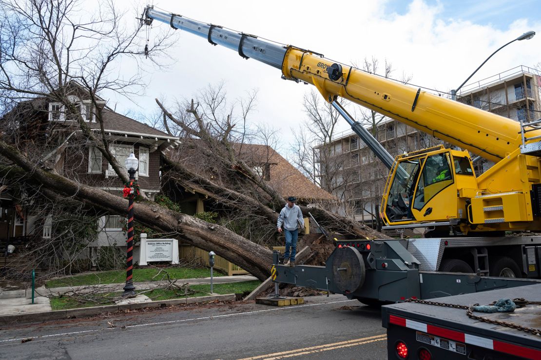 Crane operator Ricky Kapuschinsky prepares to lift uprooted trees Sunday in Sacramento, California.