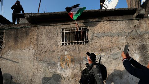 A woman waves a Palestinian flag from her window during clashes with Israeli police following on February 18, 2022.