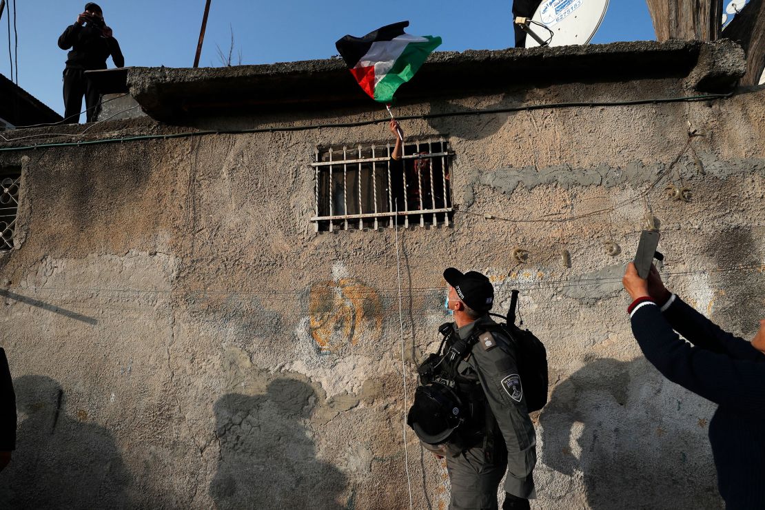 A woman waves a Palestinian flag from her window during clashes with Israeli police following on February 18, 2022.