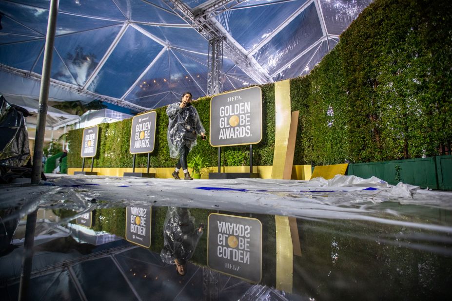 A crew member is reflected in pools of water while setting up the red carpet for the Golden Globe Awards in Los Angeles.