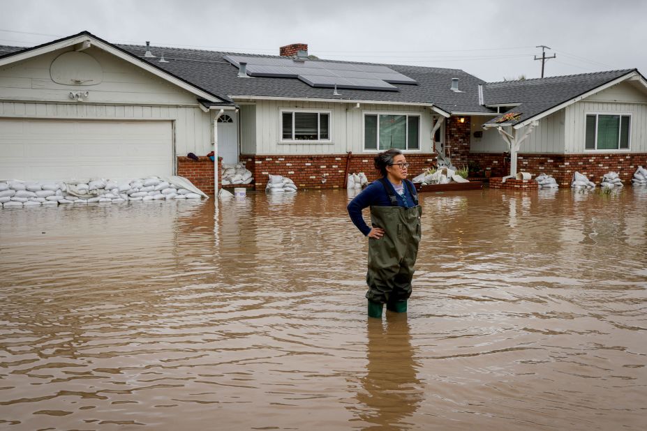 Colleen Kumada-McGowan stands in floodwaters in front of her home in Watsonville on Monday.