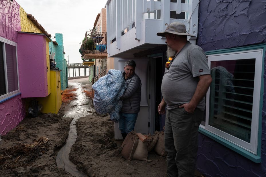 Santa Cruz residents clear storm debris and stack sandbags near their homes on Saturday.